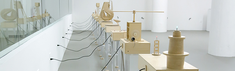 Tables with wooden sculptures, each with a cord plugged into a wall